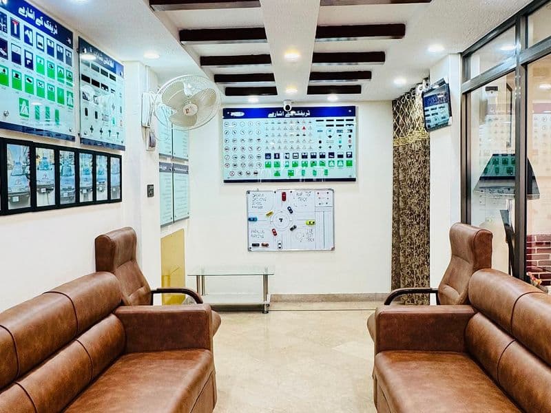 PWD Road Branch (Head Office) — The waiting area at the PWD Road branch — two leather sofas facing each other, with road-sign boards and a practice whiteboard on the wall behind