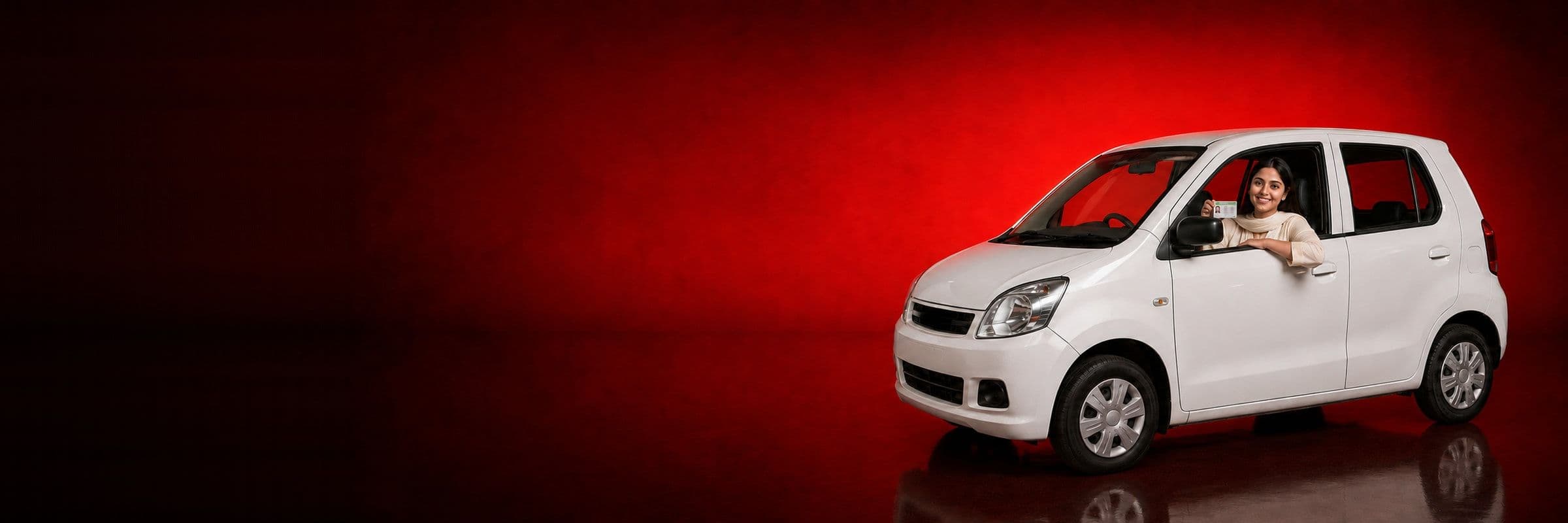 A student in a white car holding up her new driving licence, on a red studio backdrop