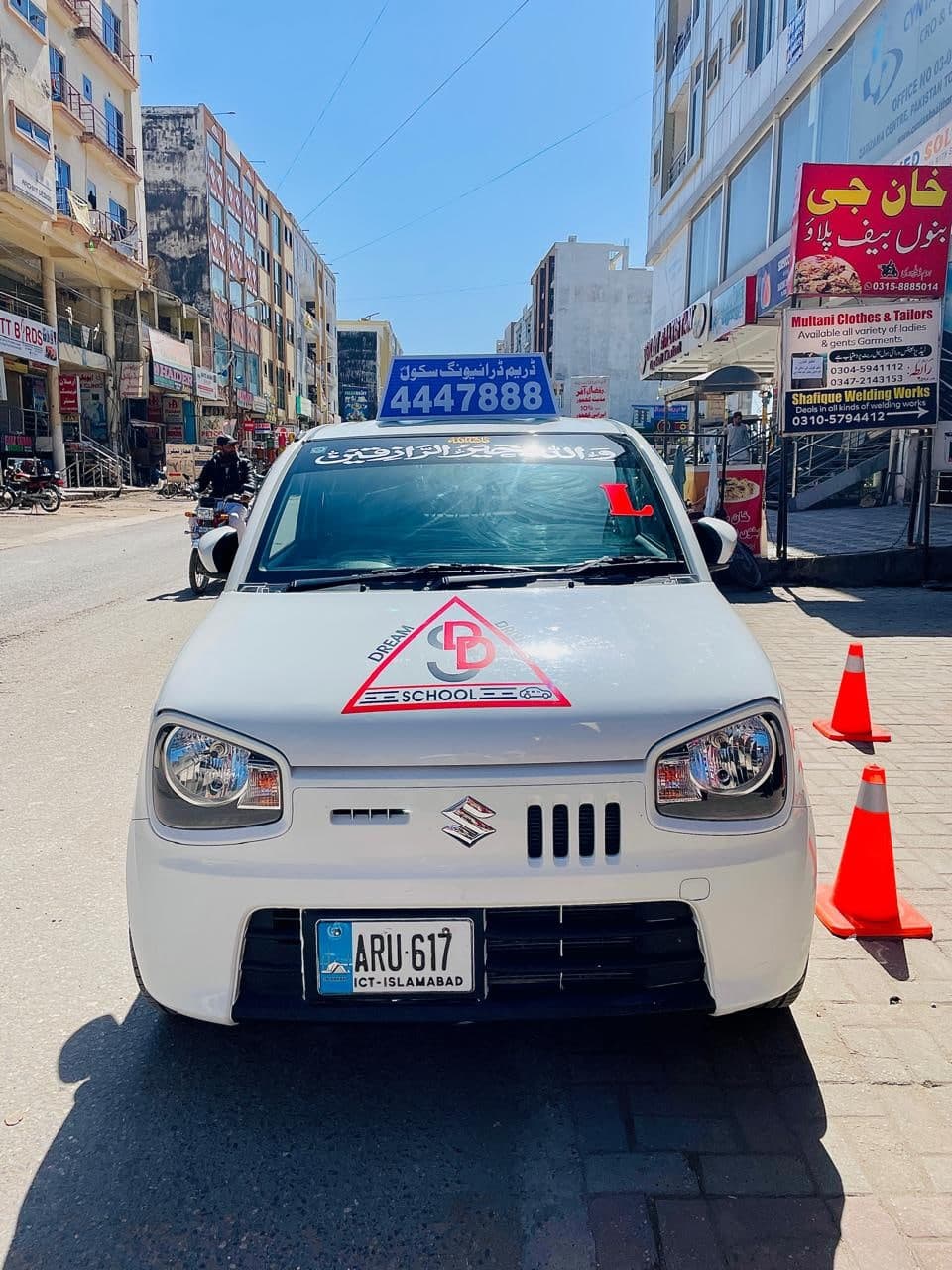 A Dream Driving School training car in traffic with its roof sign showing the school number
